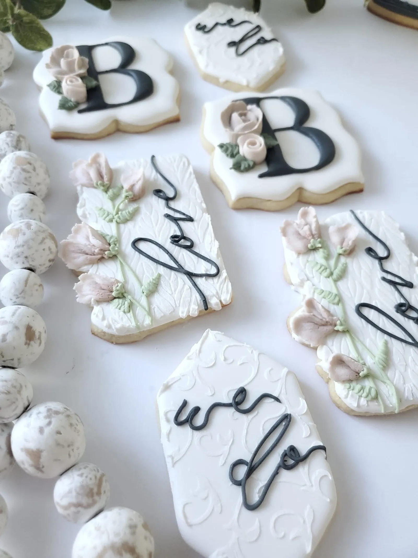 White wedding cookies with B monograms, love script and a we do plaque, with sugared almonds.