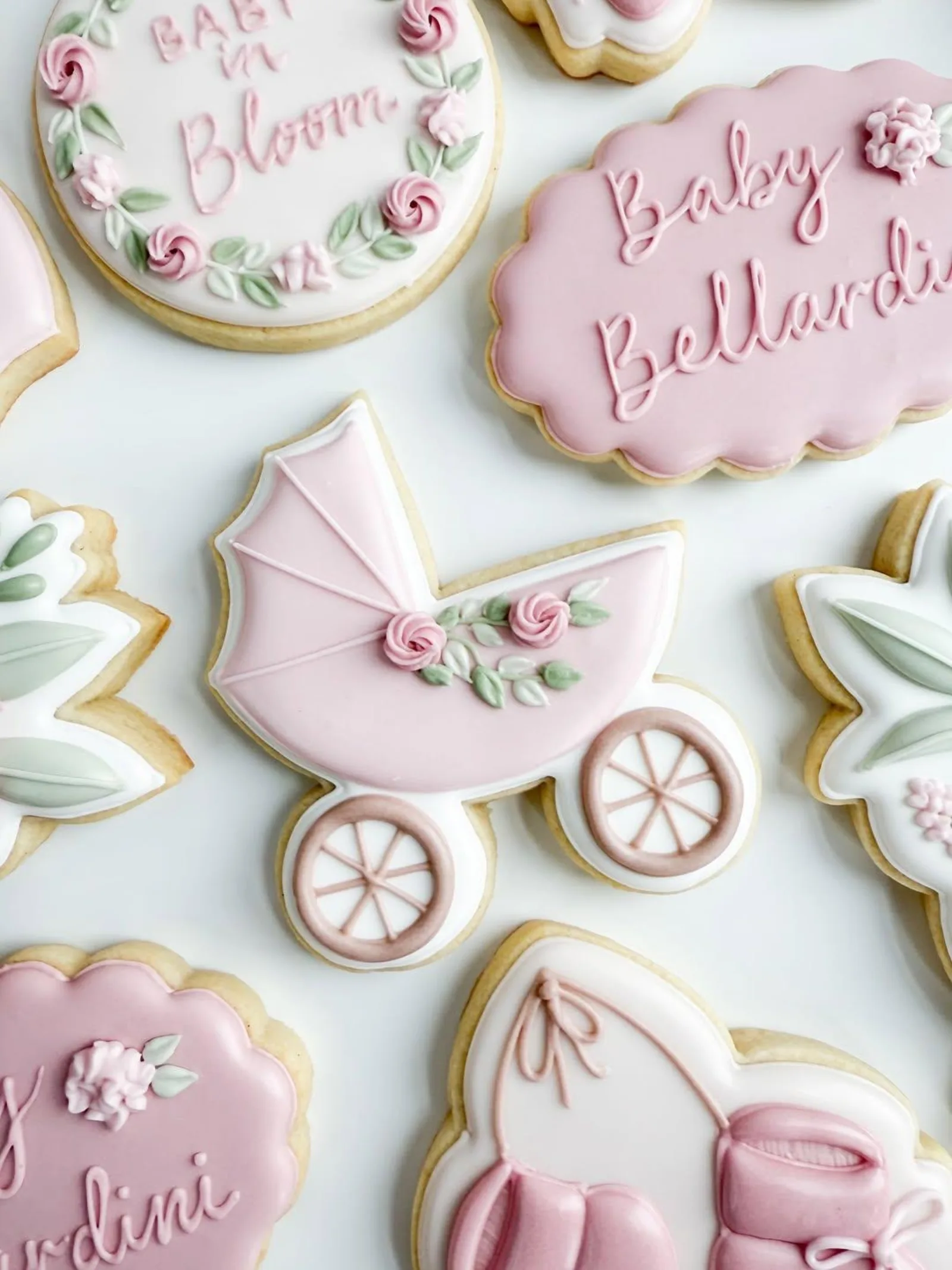 Baby shower cookies in pink and green with a carriage, a Baby in Bloom wreath and name plaques.
