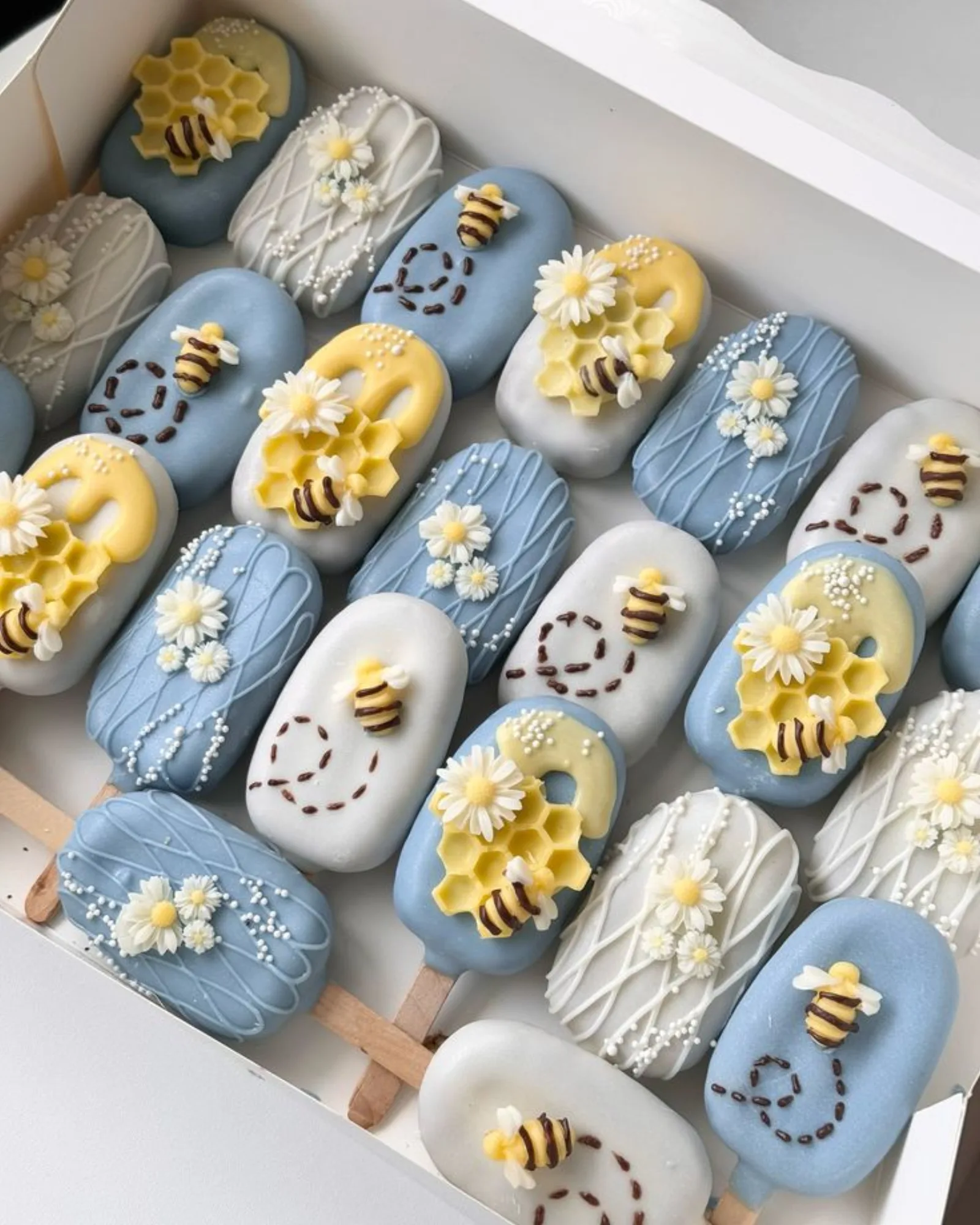 Heart-shaped pretzels dipped in white and yellow chocolate, decorated with fondant bees and honeycomb pieces.