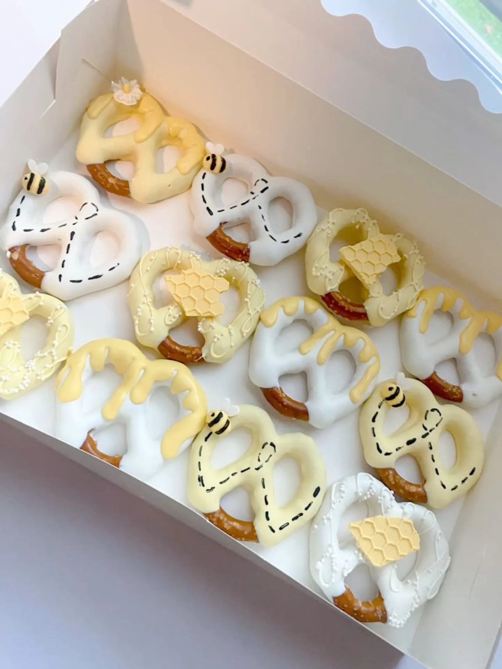 Pretzel rods dipped in white chocolate with a honey drizzle top, decorated with fondant bees on a flight path.