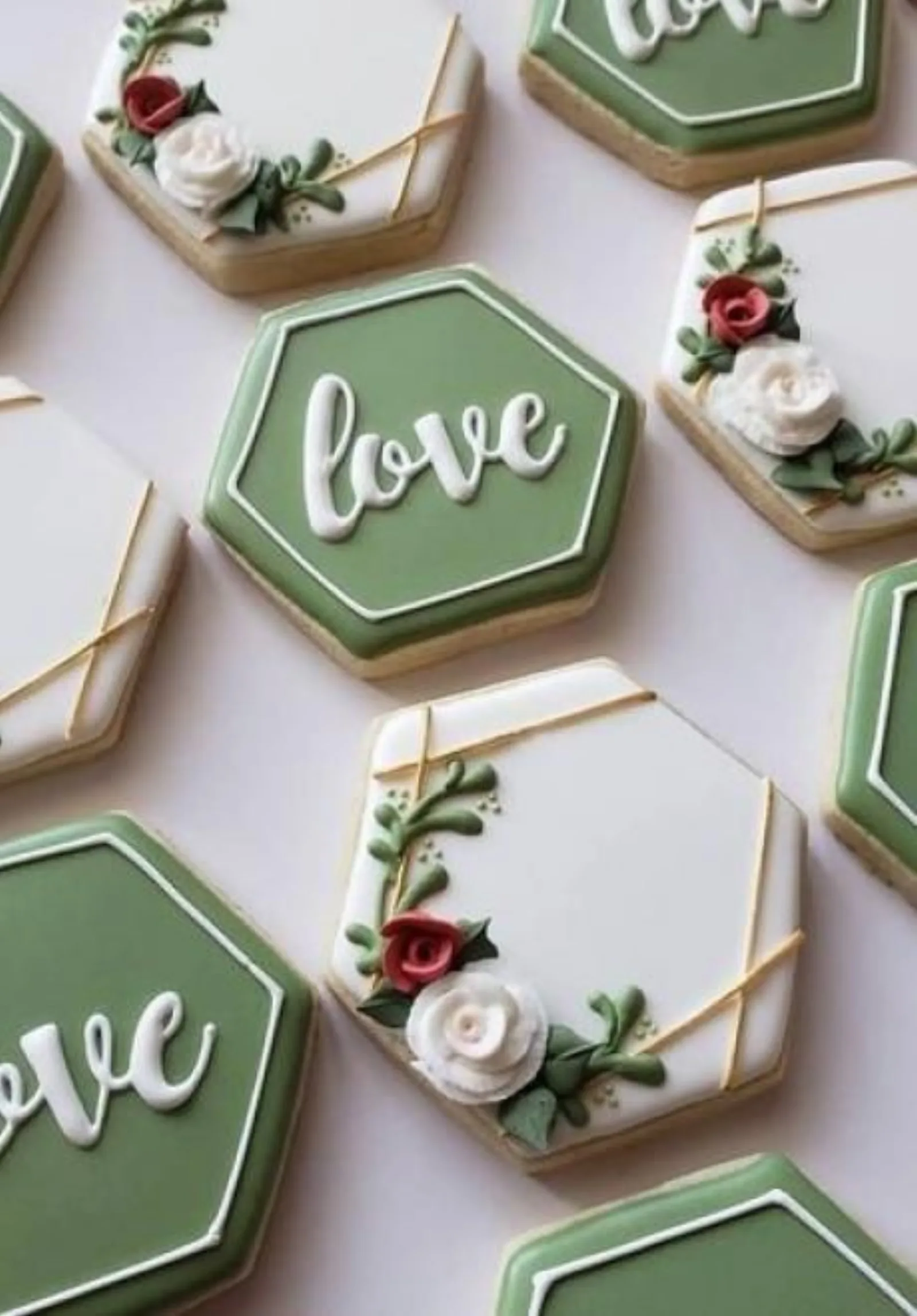 Sage green and white hexagon cookies with love script, gold lines and piped roses.