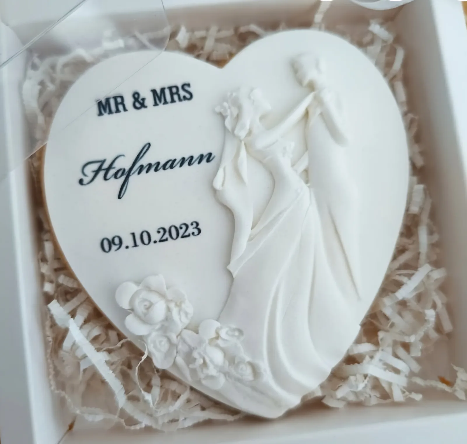 White heart cookie embossed with a bride and groom, reading Mr and Mrs with the wedding date, in a gift box.