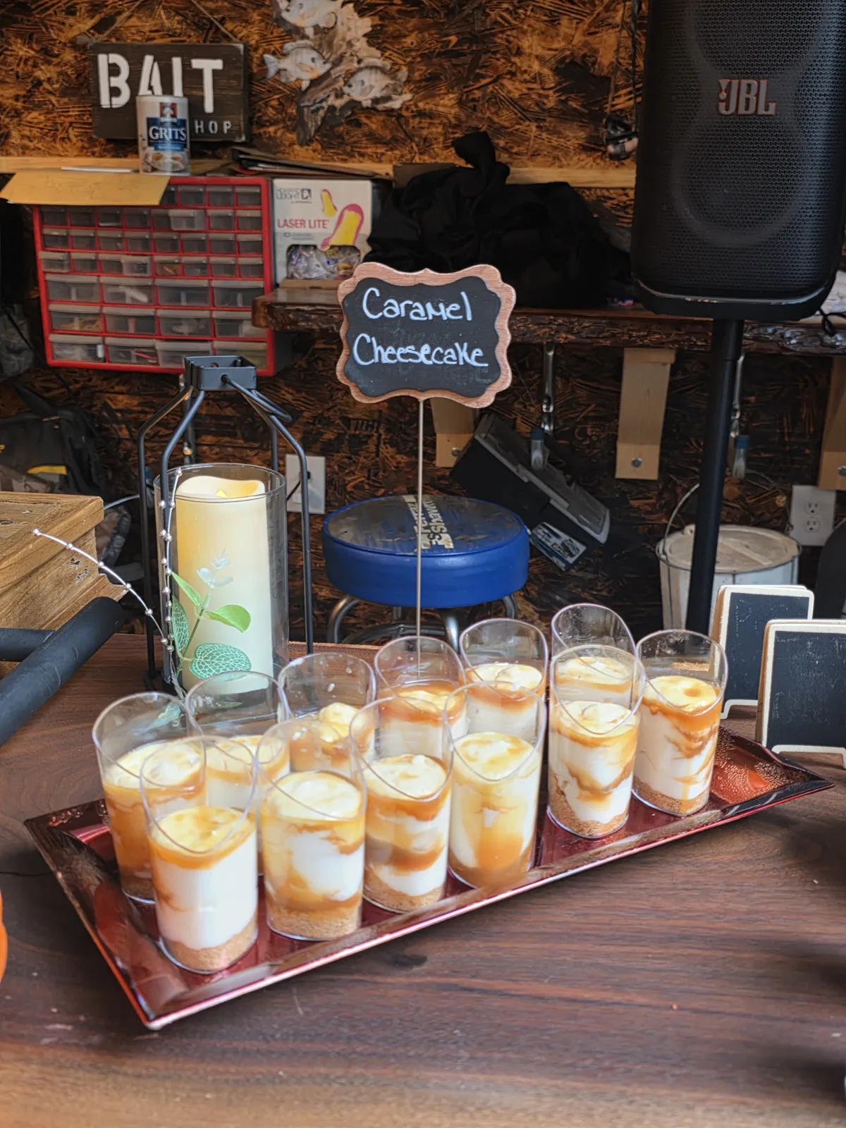 Caramel cheesecake dessert cups lined up on a copper tray with a chalkboard sign.