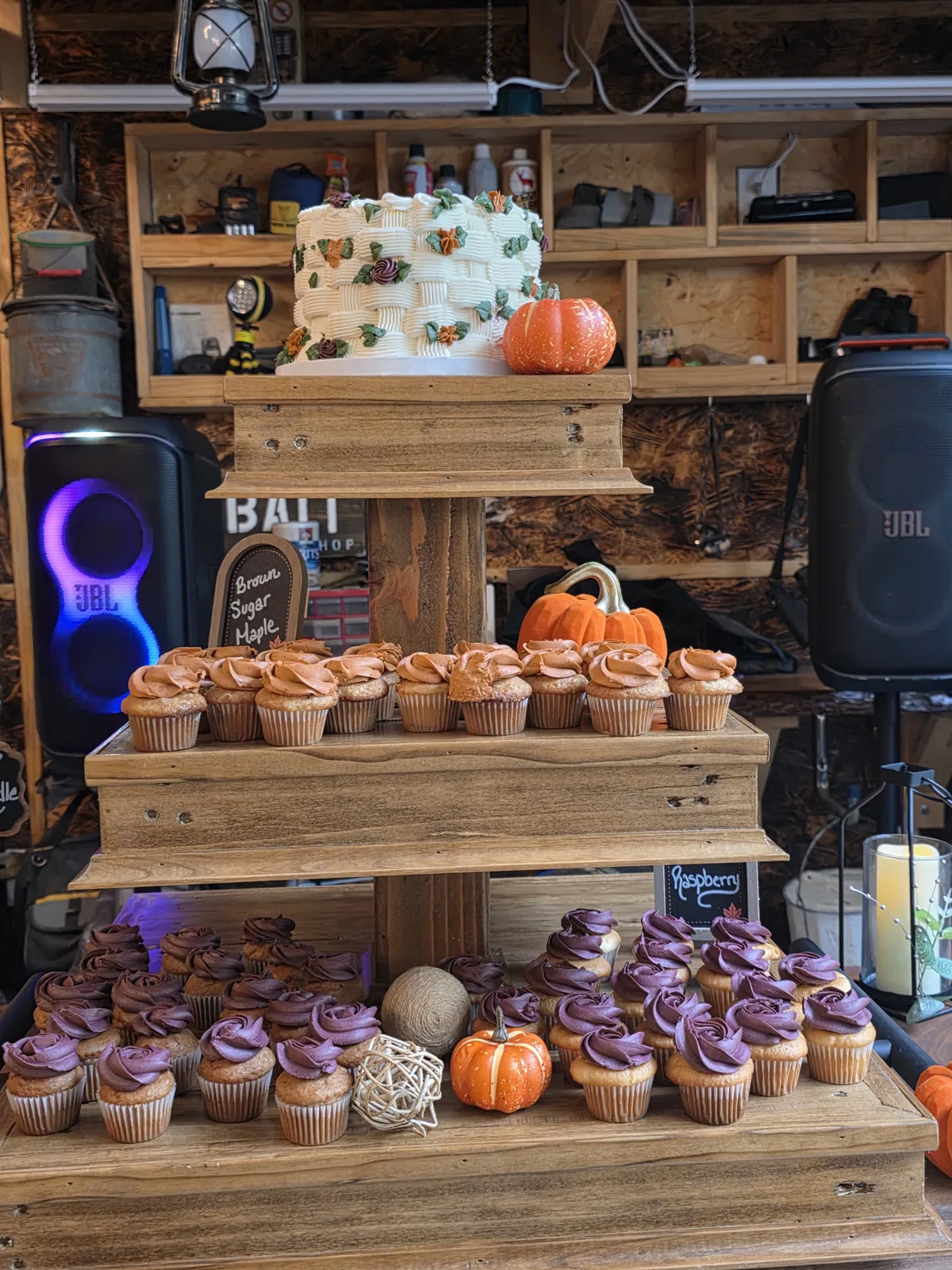 Fall wedding dessert table with a basket weave cake on top and tiers of brown sugar maple and raspberry cupcakes with pumpkins.