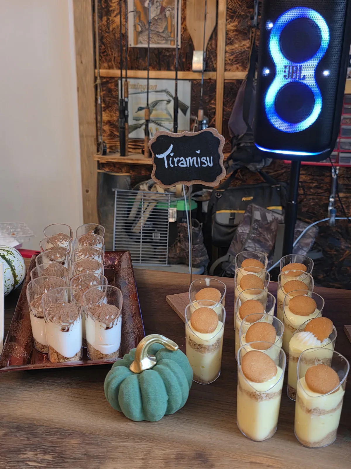 Tiramisu dessert cups on a rustic dessert table with pumpkins and a chalkboard sign.